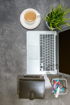 Top view of business desk with laptop, coffee, potted plant, notebook and business accessories on the office