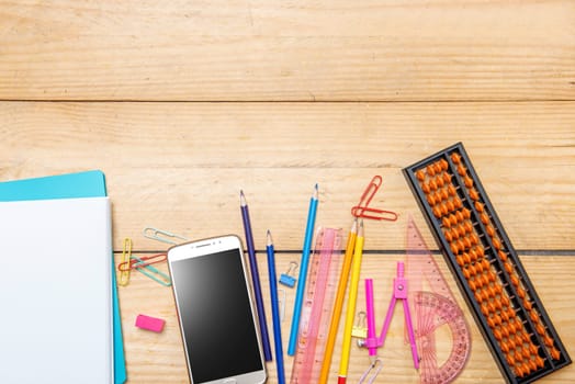 Notebooks and mobile phone with school supplies and stationery on the wooden table. Back to School concept