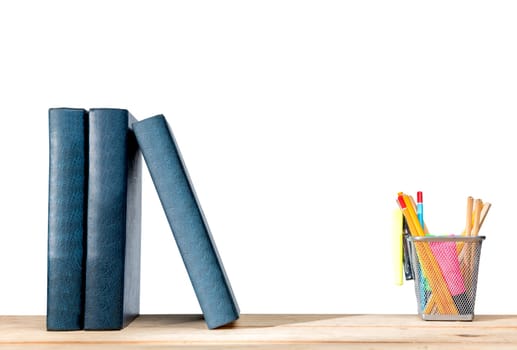 Pile of books standing and pencils in basket container with green stapler on wooden table isolated over white background. Back to School concept