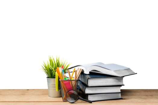 Pile of books with potted plant and pencils in basket container with magnifying glass on wooden table isolated over white background. Back to School concept