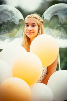 portrait of young girl with balloons on nature background.