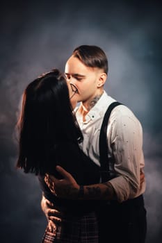 Couple in fashionable clothes on a dark smoky background.