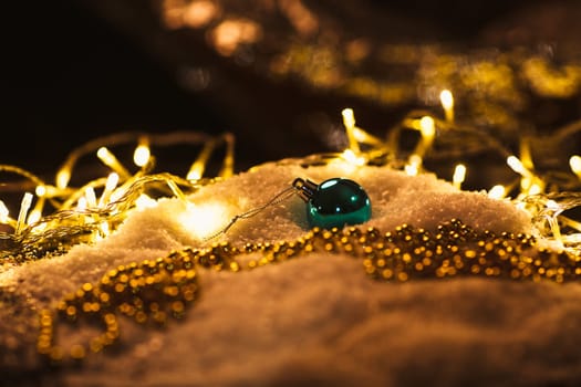 blue Christmas ball and luminous garland on the snow.