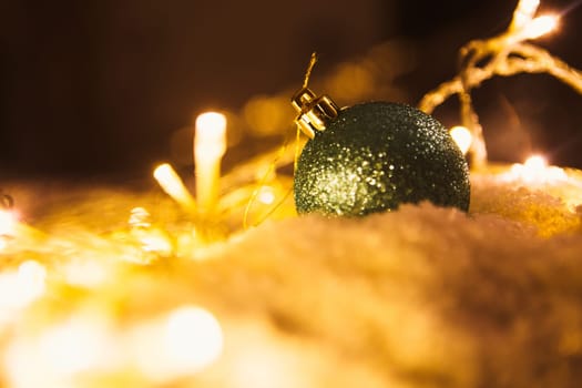 blue Christmas ball and luminous garland on the snow.