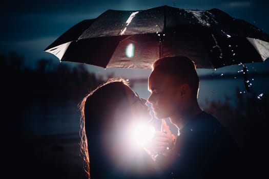young man and woman under an umbrella and rain.