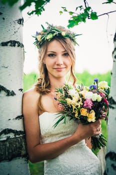 Young bride near birches in the forest.