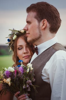 portrait bride and groom stand on the background of the field.