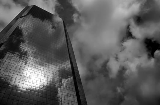 Skyscraper glass facade with reflection of sky and clouds. Concept of modernity and business. Black and white photography.
