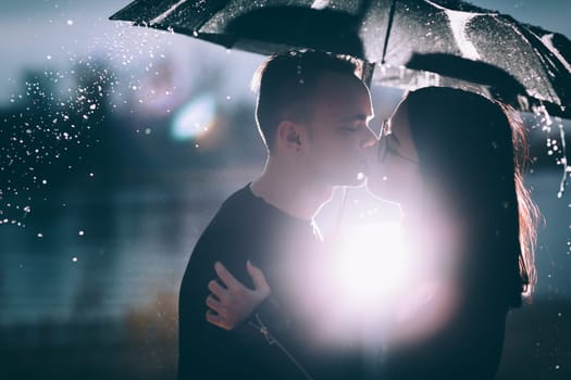 young couple standing under a dark umbrella.
