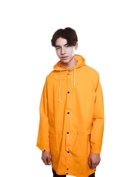 portrait of a teen guy in a yellow raincoat brunette in the studio.
