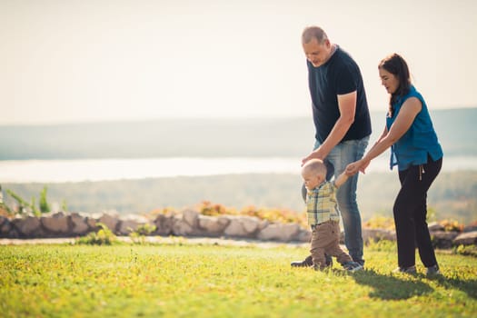 Happy family with baby on green grass.