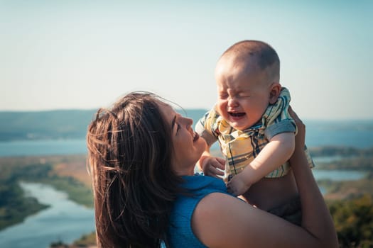 mother and crying toddler son on nature background.