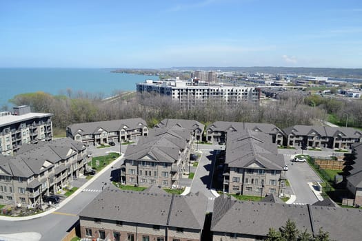An aria view of some big development with new houses and condo.buildings on the shore of lake Ontario on a sunny spring day.