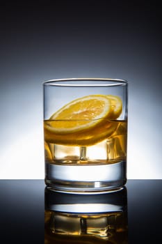 Glass of cocktail with ice-cubes and lemon, isolated.