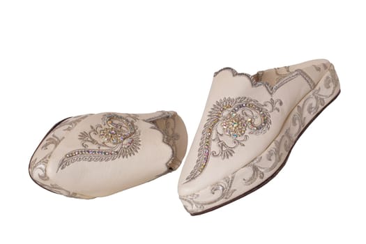 Slippers woman isolated. Closeup of elegant luxurious handmade beige ladies slippers with beautiful floral embroidery and rhinestones. Fashionable shoes.