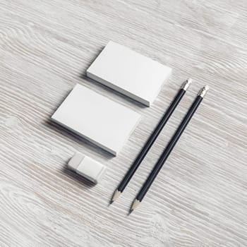 Blank stationery set on light wooden background. Photo of blank business cards, pencils and eraser.