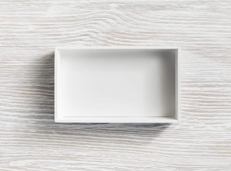 Blank white opened box on light wooden background. Flat lay.