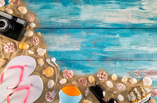 Beach accessories retro film camera sunglasses flip flop and sea shell on wooden. Top view of beach accessories on blue plank summer holiday banner travel concept. Focus on shells.