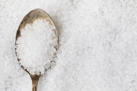 Salt crystals in metalspoon on bed of salt.