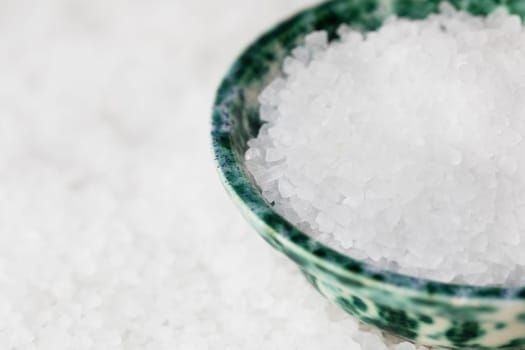 Salt crystals in green bowl on bed of salt.