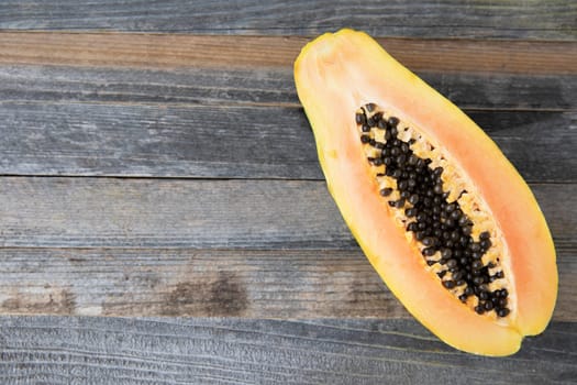 Half a papaya on a wooden surface with copy space.