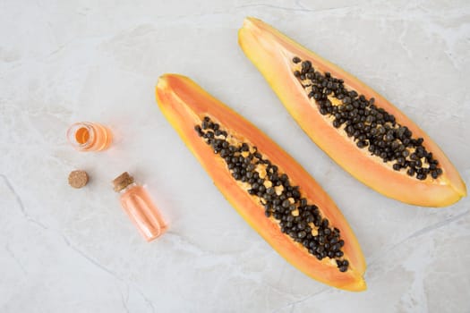 Quarter slices papaya on a marble surface with small bottles of papaya extract.