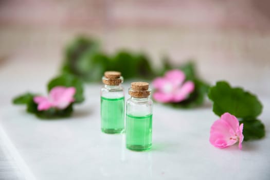 Plant extract in viles with geranium leaves and pink flowers