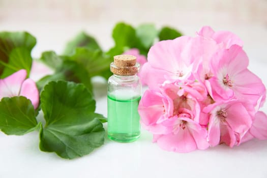 Plant extract in viles with geranium leaves and pink flowers