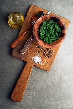 Spring healthy food with vegetables and herbs. Green pesto for healthy meal on gray background