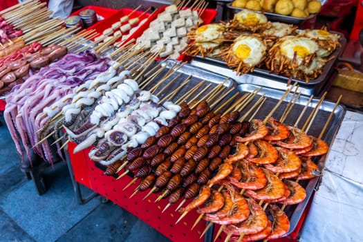 Roasted, fried and raw insects, silkworms, scorpions, bugs, snakes, dog meat, octopus on stick as snack street food in China