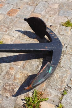 Black iron anchor, lying on the ground
