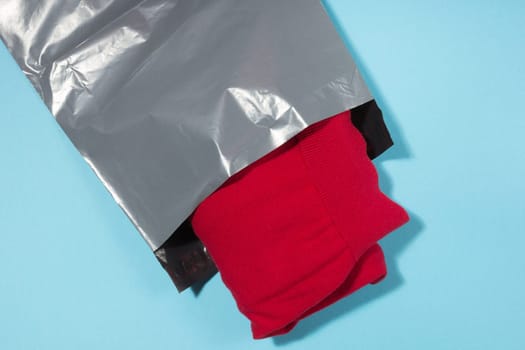 red jumper packed in gray mailing bag
