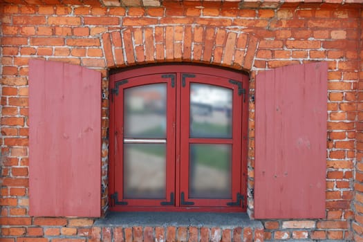Classic wooden window with shutters on red brick wall