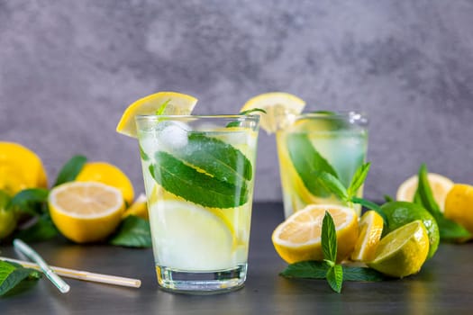 Cold refreshing summer lemonade with mint in a glass on a grey and black background. Focus on glass.