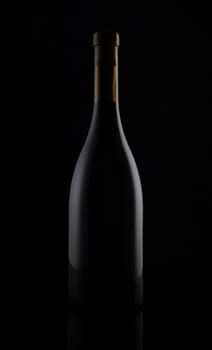 Isolated black matt wine bottle on dark background.