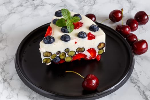 Berry dessert with blueberries and strawberries on the basis of yogurt on a black ceramic dish decorated with berries and mint