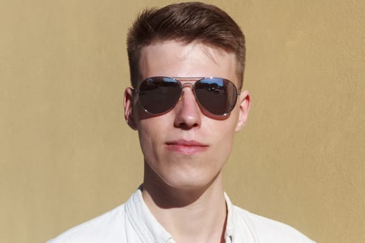 portrait of a handsome man dressed in white shirt against yellow wall