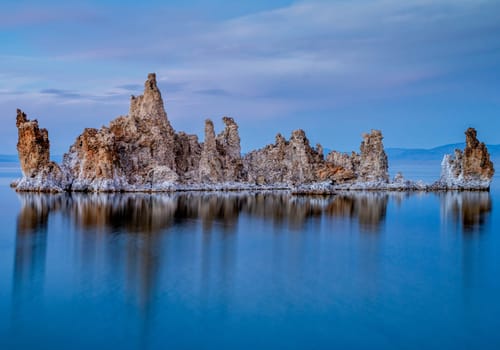 Ancient lake in a crater of an extinct volcano. Tufa stalactites are reflected in smooth water of lake