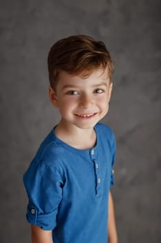 5 year old boy blue shirt and yellow pants studio portrait on gray background.