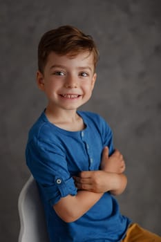 5 year old boy blue shirt and yellow pants studio portrait on gray background.