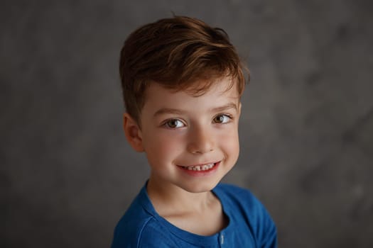 5 year old boy blue shirt and yellow pants studio portrait on gray background.