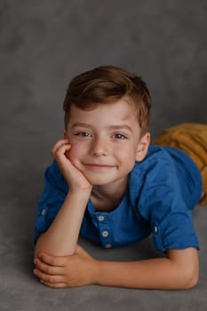 5 year old boy blue shirt and yellow pants studio portrait on gray background.