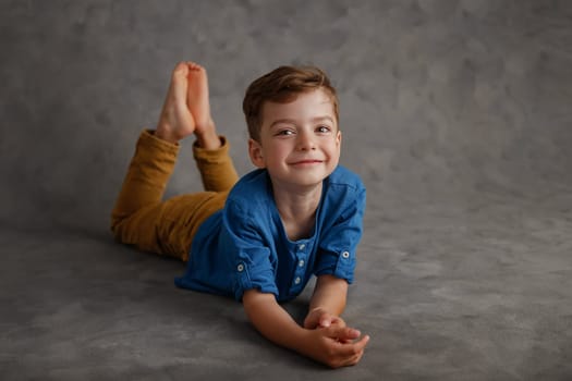 5 year old boy blue shirt and yellow pants studio portrait on gray background.
