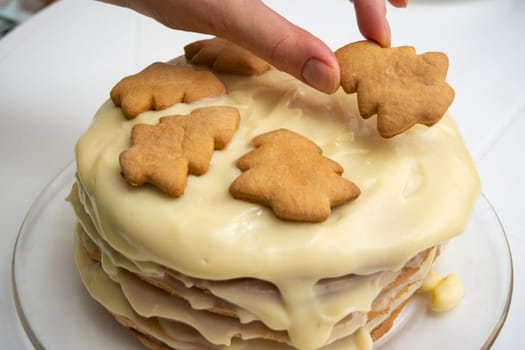 Homemade cake with condensed milk, a hand on top puts a Christmas tree cookie