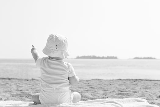 Baby Pointing to the Sky by Ocean in black and white.