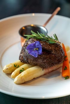 Grilled Beef Tenderloin wagyu with white asparagus decorate with edible flowers