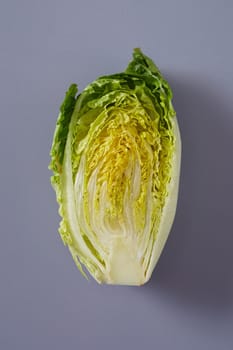 Cross section through a head of fresh Chinese Cabbage or Napa Cabbage showing the arrangement of the crinkly green leaves for salad or cooking over grey