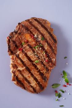 Portion of lean tender marinated grilled beef steak seasoned with fresh herbs, spices and salt on a blue grey background viewed from above