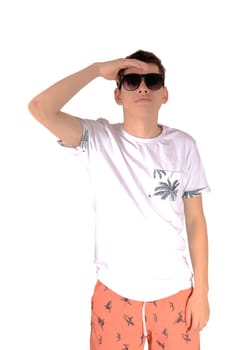 A tall young teenager boy in a white shirt and Bermuda shorts wearing.sunglasses looking fare away, isolated for white background.