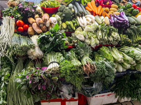 A counter with fresh vegetables in a Chinese market, farm products, greens and vegetables